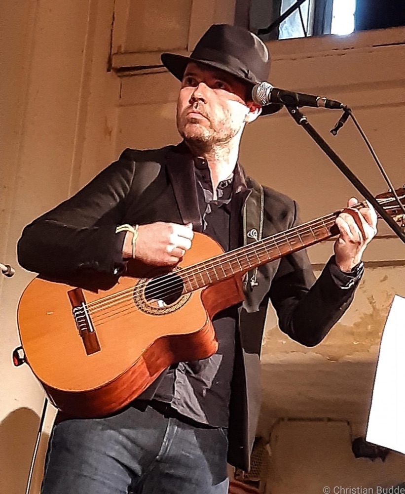 Benjamin Priebst mit schwarzem Hut spielt klassische Gitarre