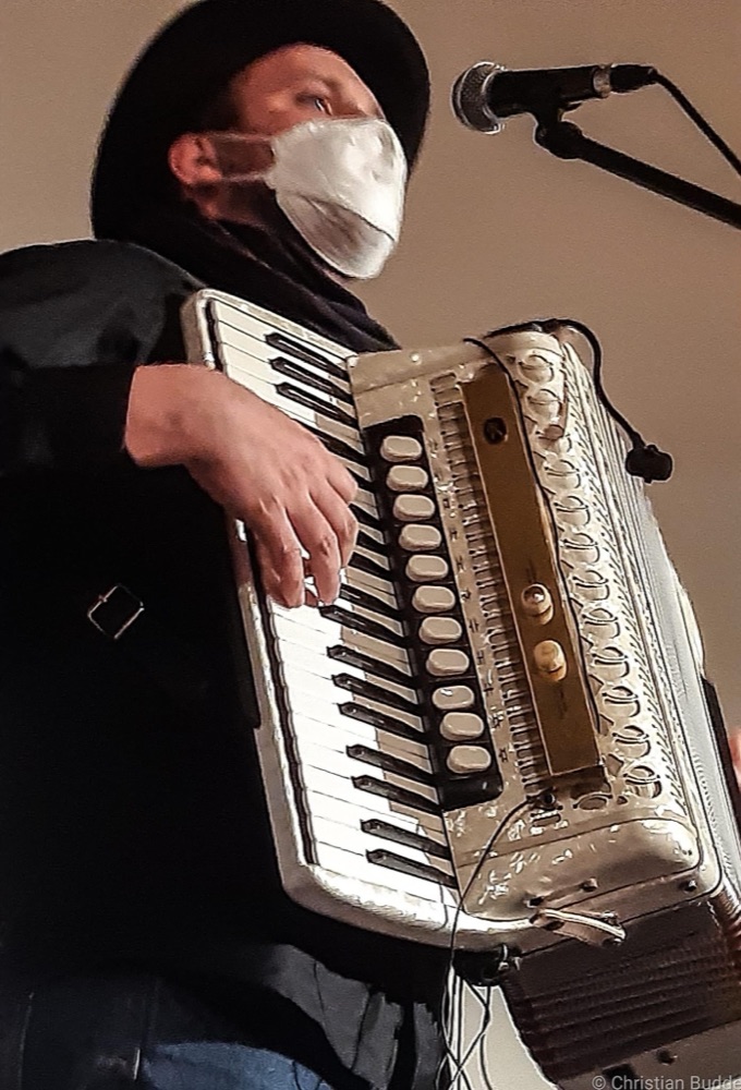 Georg Schumann spielt ein weißes Akkordeon vor einem Mikrofon